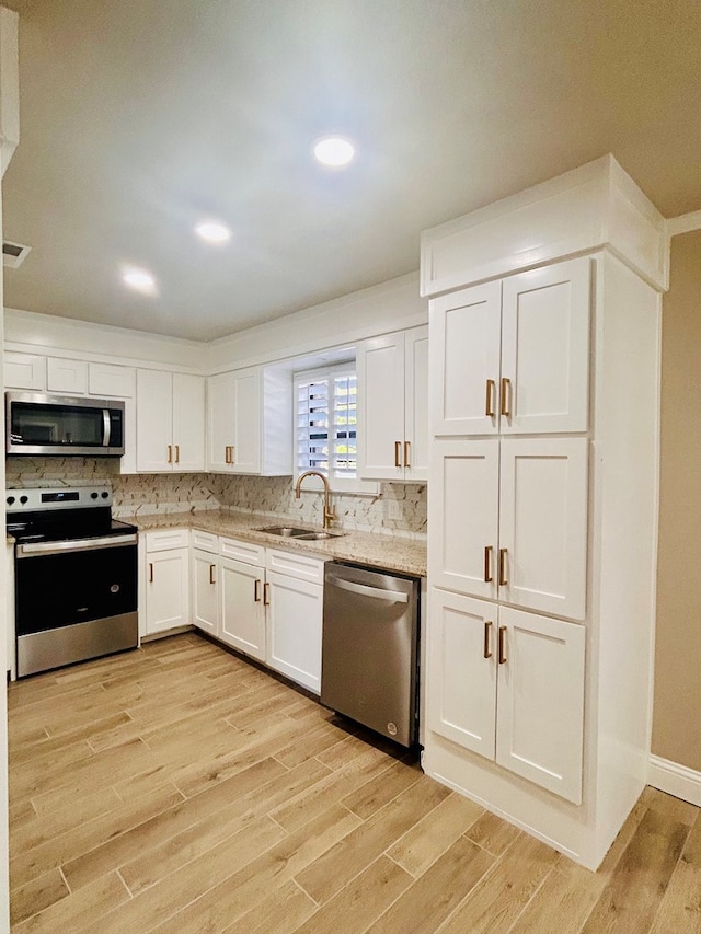 kitchen with white cabinetry, sink, light wood-type flooring, and appliances with stainless steel finishes