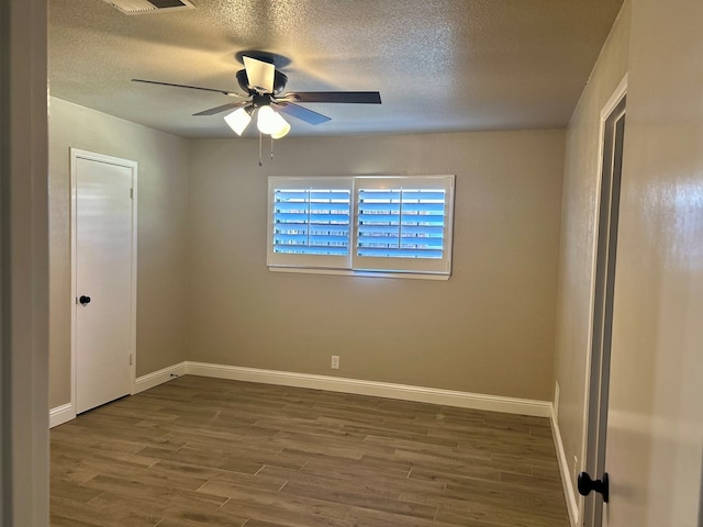 empty room with ceiling fan, dark hardwood / wood-style flooring, and a textured ceiling