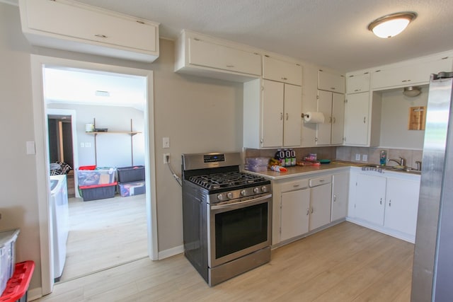 2101 Grace St, Big Spring, TX 79720 - kitchen featuring stainless steel appliances, light wood-type flooring, light countertops, and white cabinetry