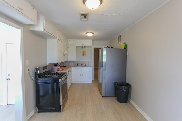 2101 Grace St, Big Spring, TX 79720 - kitchen with stainless steel appliances, light wood-style flooring, white cabinets, and light countertops