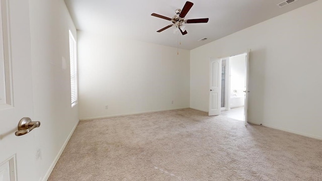 empty room with visible vents, light colored carpet, baseboards, and a ceiling fan