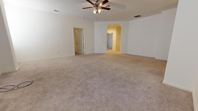 spare room with light colored carpet, arched walkways, visible vents, and ceiling fan