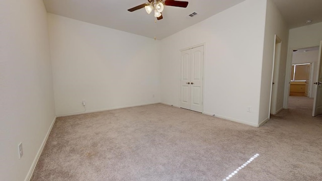 carpeted spare room featuring a ceiling fan, visible vents, and baseboards