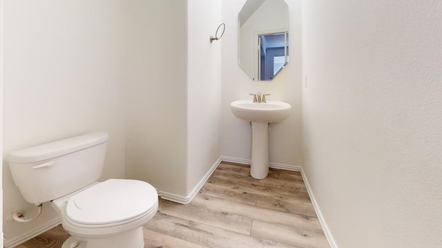 bathroom featuring a sink, toilet, baseboards, and wood finished floors