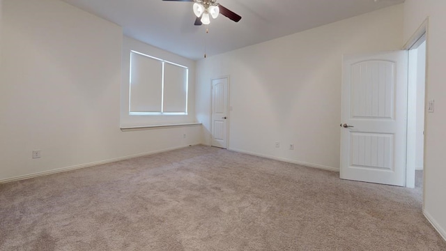 carpeted spare room with baseboards and a ceiling fan