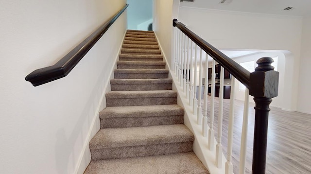 stairs with visible vents, crown molding, baseboards, and wood finished floors