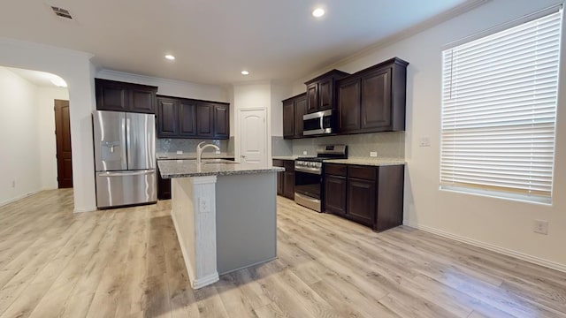 kitchen with dark brown cabinetry, light wood-style floors, appliances with stainless steel finishes, and a sink