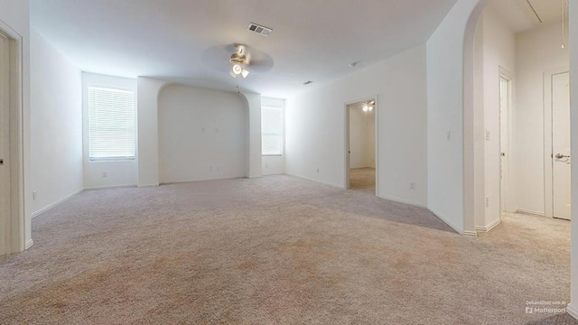 unfurnished room featuring visible vents, carpet floors, arched walkways, attic access, and ceiling fan