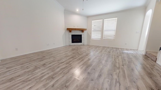 unfurnished living room featuring light wood finished floors, baseboards, ornamental molding, a glass covered fireplace, and a ceiling fan