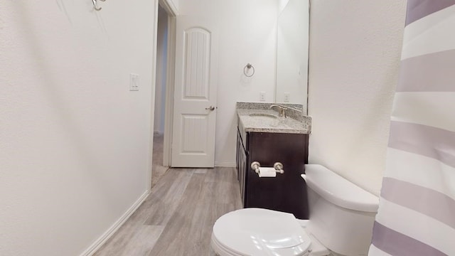 bathroom with baseboards, toilet, wood finished floors, and vanity