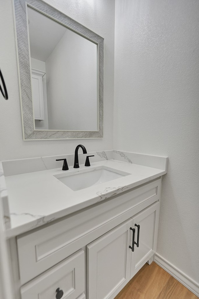 bathroom with baseboards, wood finished floors, and vanity