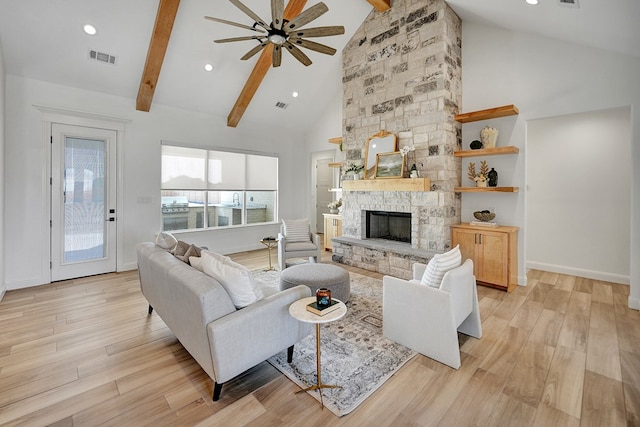 living room featuring high vaulted ceiling, light wood-type flooring, beamed ceiling, and a stone fireplace