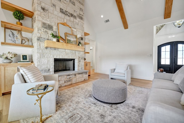 living area with high vaulted ceiling, a fireplace, light wood-style floors, french doors, and beamed ceiling