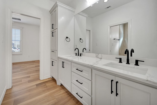 full bath featuring double vanity, visible vents, a sink, and wood finished floors