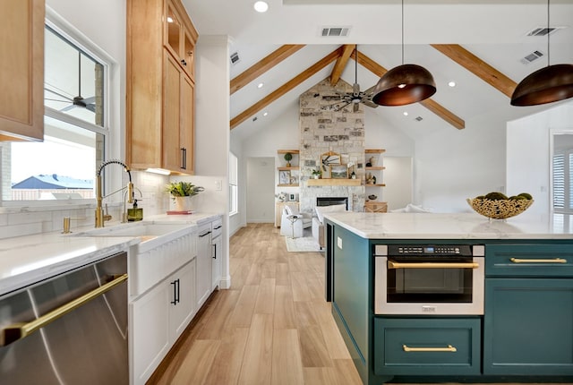 kitchen with appliances with stainless steel finishes, open floor plan, ceiling fan, a sink, and beamed ceiling