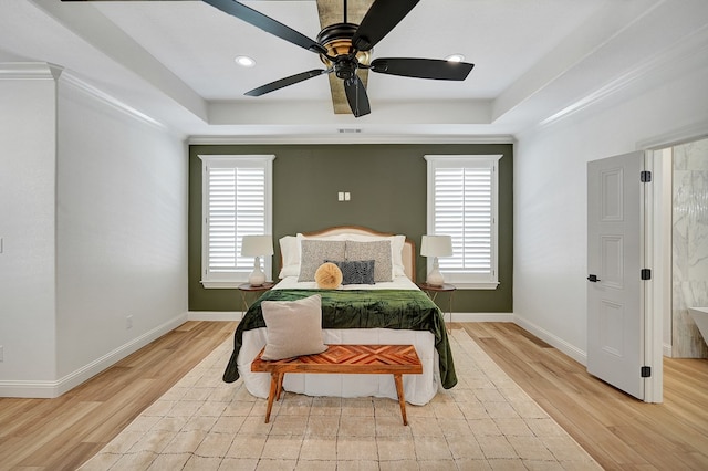 bedroom with a raised ceiling, multiple windows, and crown molding