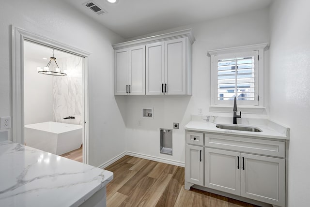 washroom featuring hookup for a washing machine, cabinet space, visible vents, a sink, and light wood-type flooring