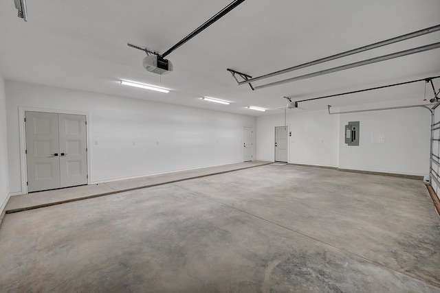 garage featuring a garage door opener, electric panel, and baseboards