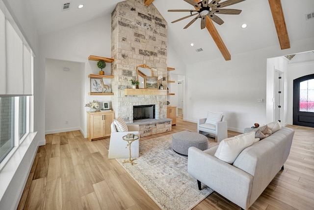 living room with visible vents, light wood-type flooring, a fireplace, high vaulted ceiling, and beam ceiling