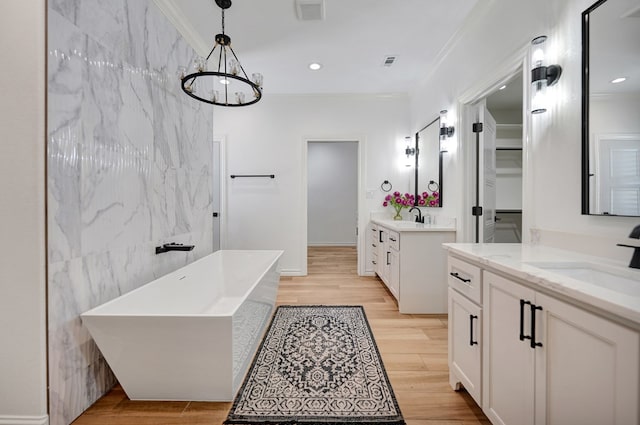 bathroom with a soaking tub, visible vents, a sink, and wood finished floors