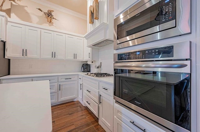 kitchen featuring white cabinetry, stainless steel appliances, crown molding, and light countertops
