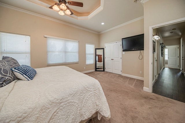 carpeted bedroom featuring ceiling fan, a tray ceiling, and crown molding