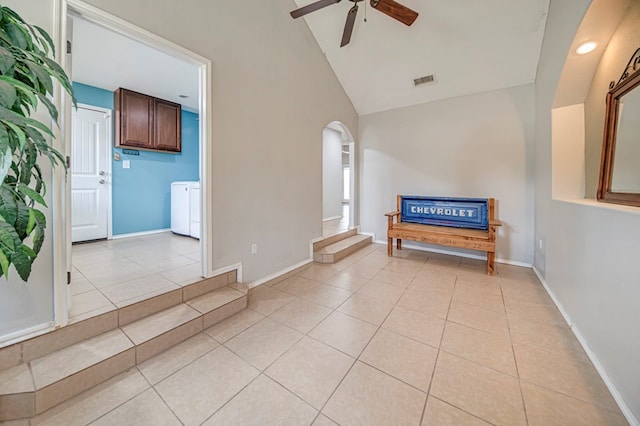 interior space featuring vaulted ceiling, ceiling fan, light tile patterned floors, and independent washer and dryer