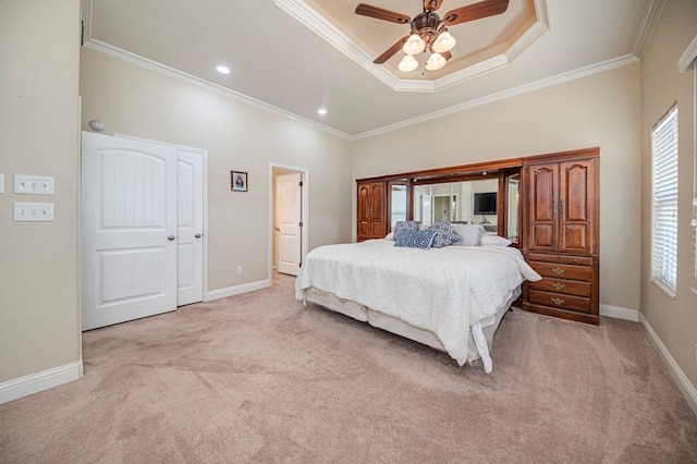 bedroom with ceiling fan, crown molding, light colored carpet, and a tray ceiling