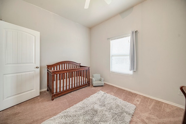 bedroom with ceiling fan, lofted ceiling, light carpet, and a crib