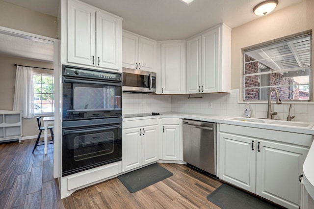 kitchen with dark wood-style floors, white cabinets, tasteful backsplash, a sink, and black appliances