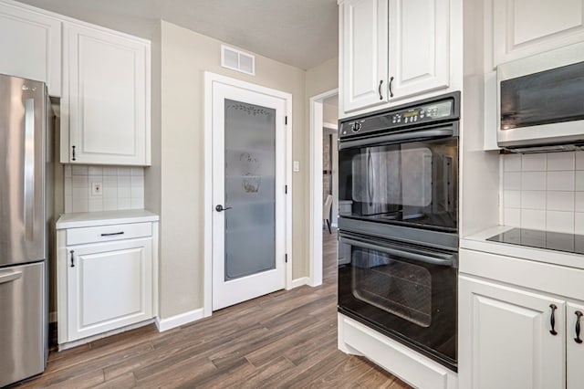 kitchen with black appliances, dark wood finished floors, white cabinetry, and visible vents
