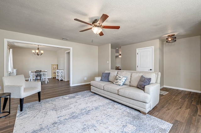 living area with baseboards, ceiling fan with notable chandelier, dark wood finished floors, and a textured ceiling