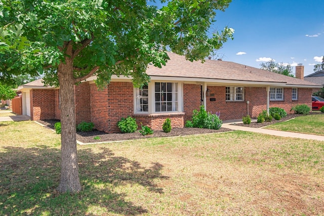 single story home with brick siding, a front lawn, and a chimney
