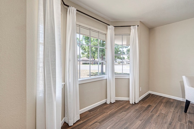 empty room with baseboards and dark wood-type flooring