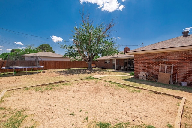 view of yard featuring a fenced backyard, a trampoline, and a patio area