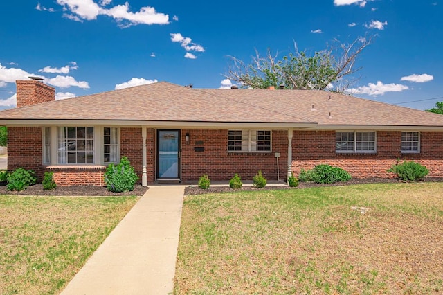 ranch-style house with a chimney, brick siding, and a front yard