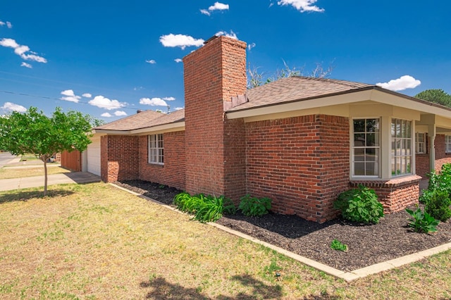 view of home's exterior with a chimney, a lawn, a garage, brick siding, and a shingled roof