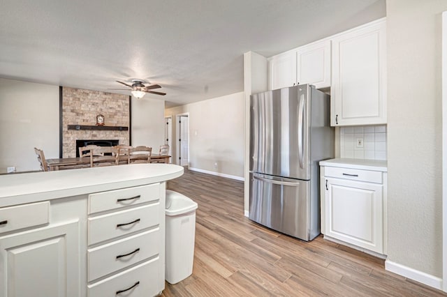 kitchen with freestanding refrigerator, light wood-style floors, ceiling fan, light countertops, and white cabinetry