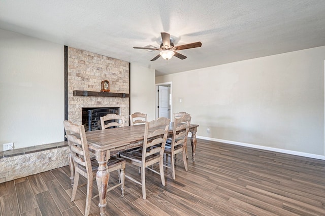 dining area featuring baseboards, a ceiling fan, wood finished floors, and a fireplace