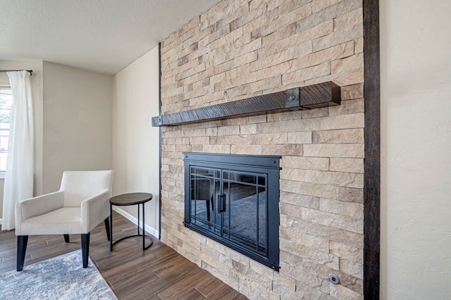 interior details featuring a large fireplace, baseboards, a textured ceiling, and wood finished floors