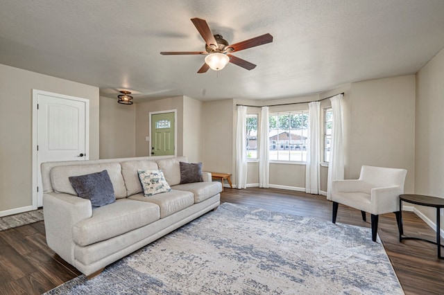 living room featuring baseboards, a ceiling fan, and dark wood finished floors