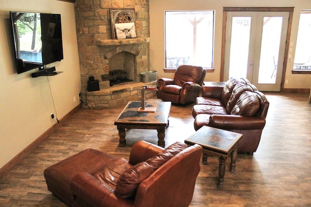 living room with a stone fireplace, french doors, and dark hardwood / wood-style floors