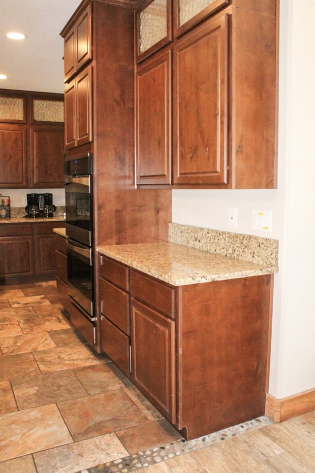 kitchen featuring light stone counters and stainless steel double oven