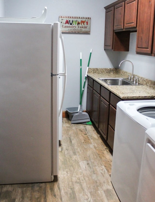 kitchen featuring dark brown cabinets, white refrigerator, light hardwood / wood-style floors, and sink