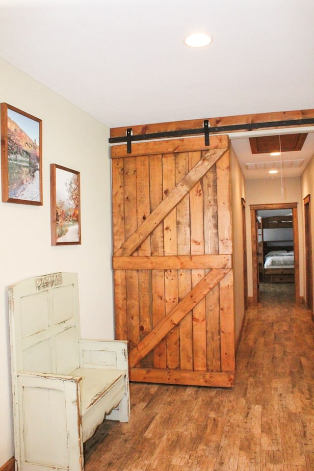 hall with a barn door and dark wood-type flooring