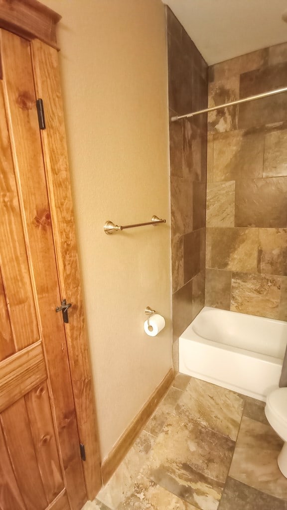 bathroom with tiled shower / bath combo and toilet