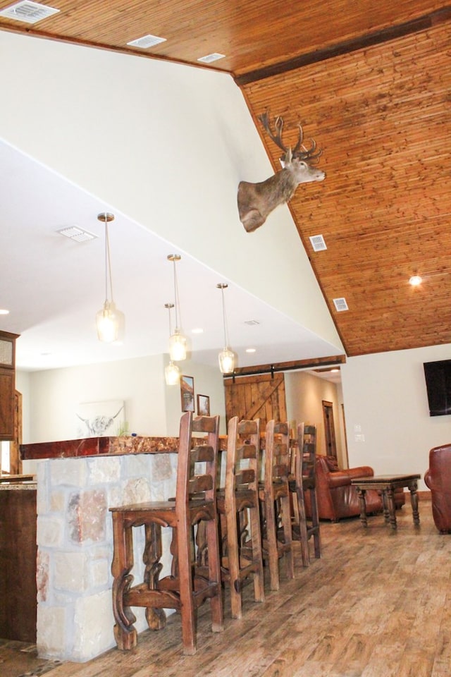 dining space featuring hardwood / wood-style floors, a barn door, wood ceiling, and vaulted ceiling