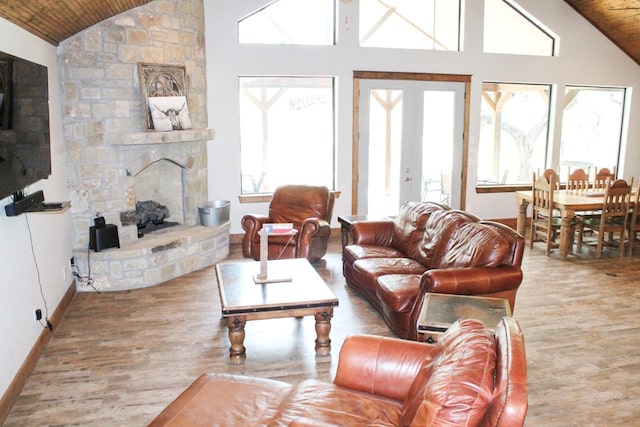 living room featuring a stone fireplace, wood ceiling, and high vaulted ceiling