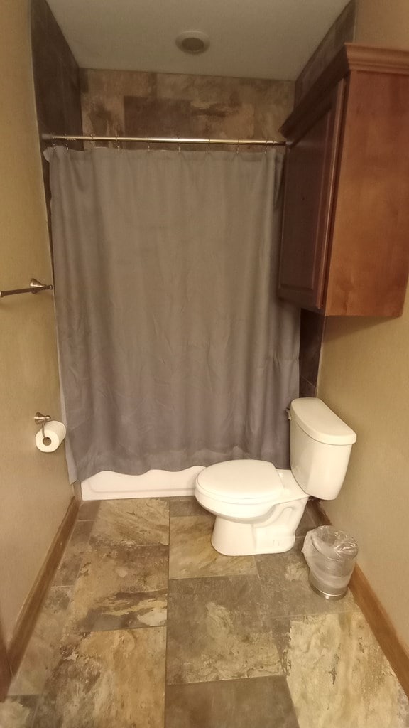 bathroom with a shower with shower curtain and toilet