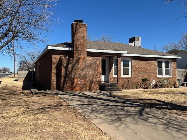 rear view of house with a chimney and brick siding